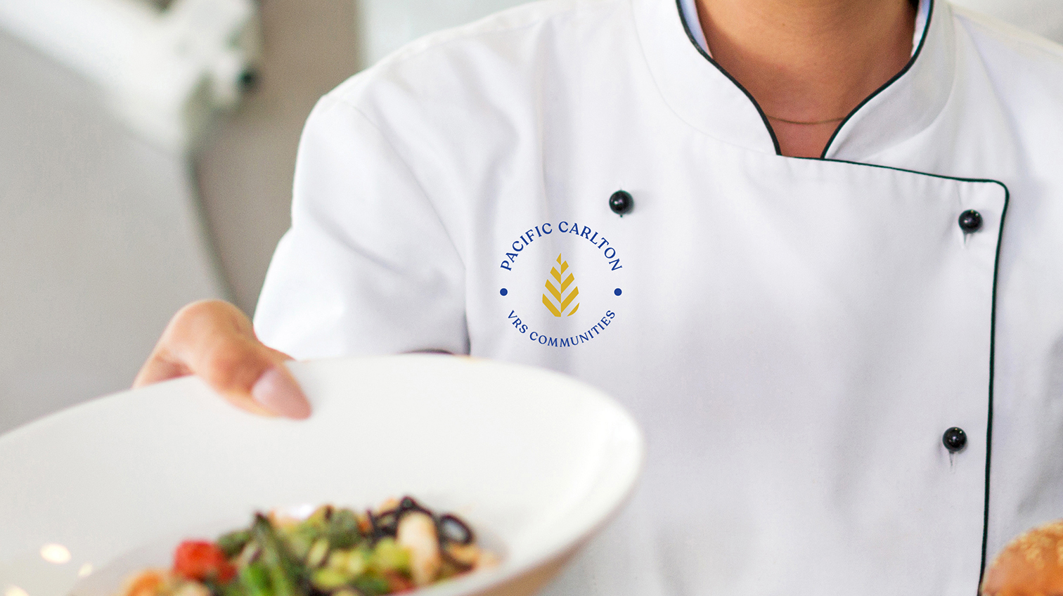 VRS Pacific Carlton logo on a Chef's uniform as she's holding a plate of food - White Canvas Design