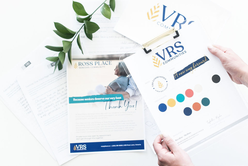 Woman holding VRS style guide sheet on a clipboard, below shows more VRS graphic designs - White Canvas Design