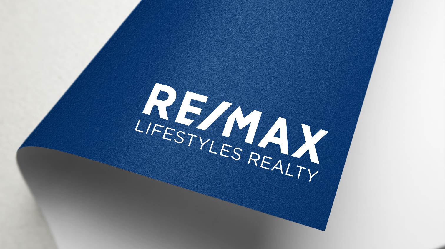 Re/max lifestyle realty logo on a piece of dark blue paper - White Canvas Design