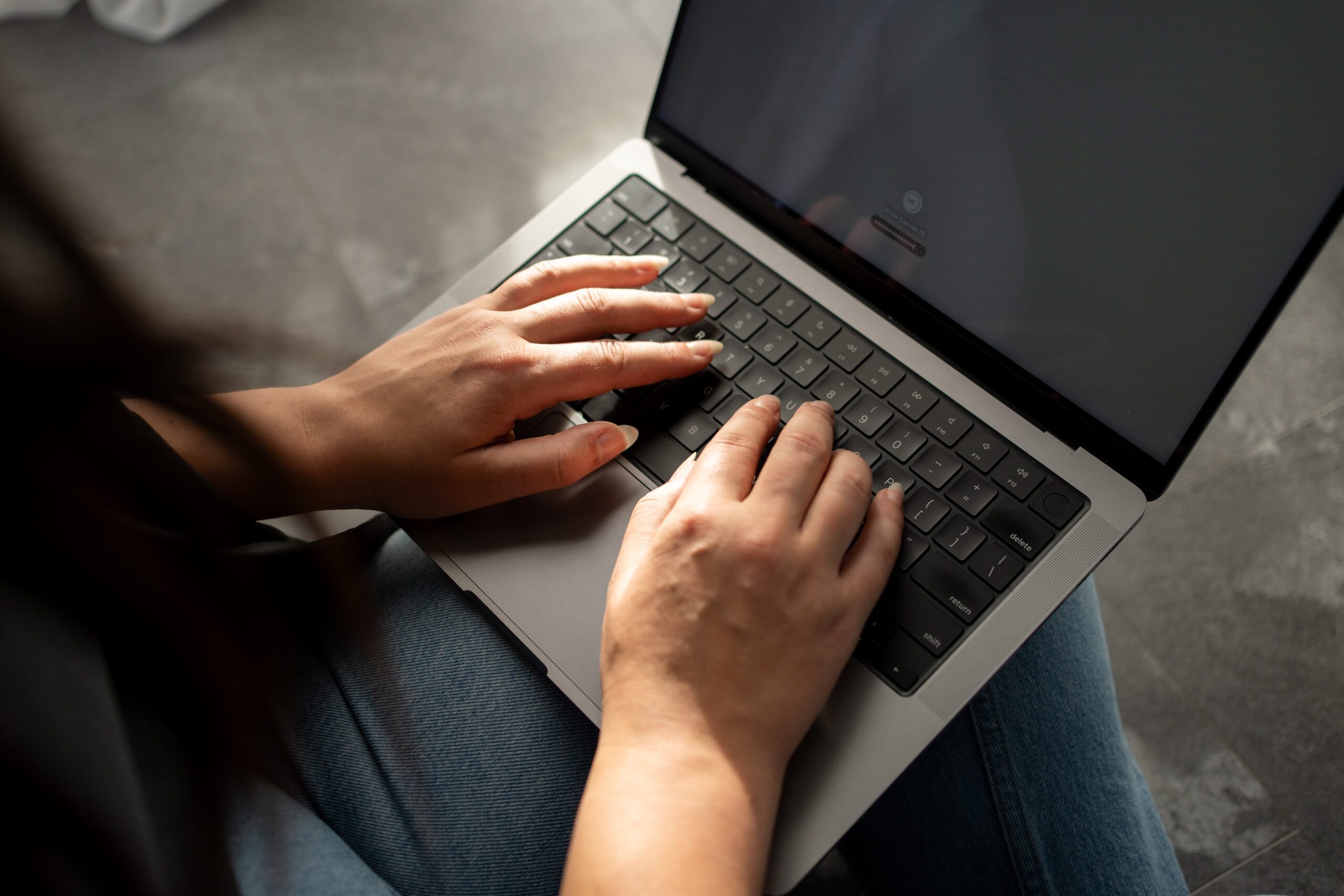 Hands typing on a laptop keyboard