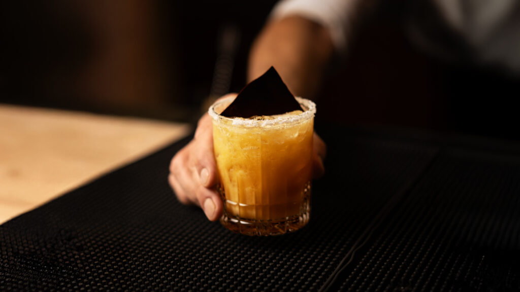 A bartender passing out a cocktail at the bar at the CinCin Restaurant