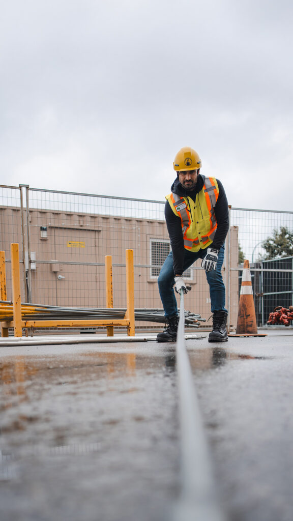 BCMEA crew member in safety gear pulling on an industrial wire