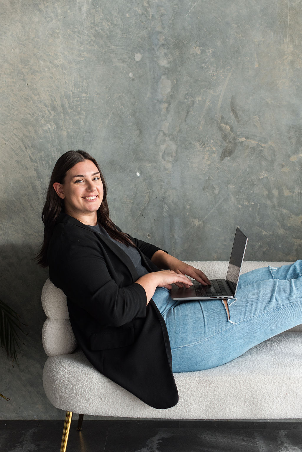 Kelsi sitting on a sofa with a laptop