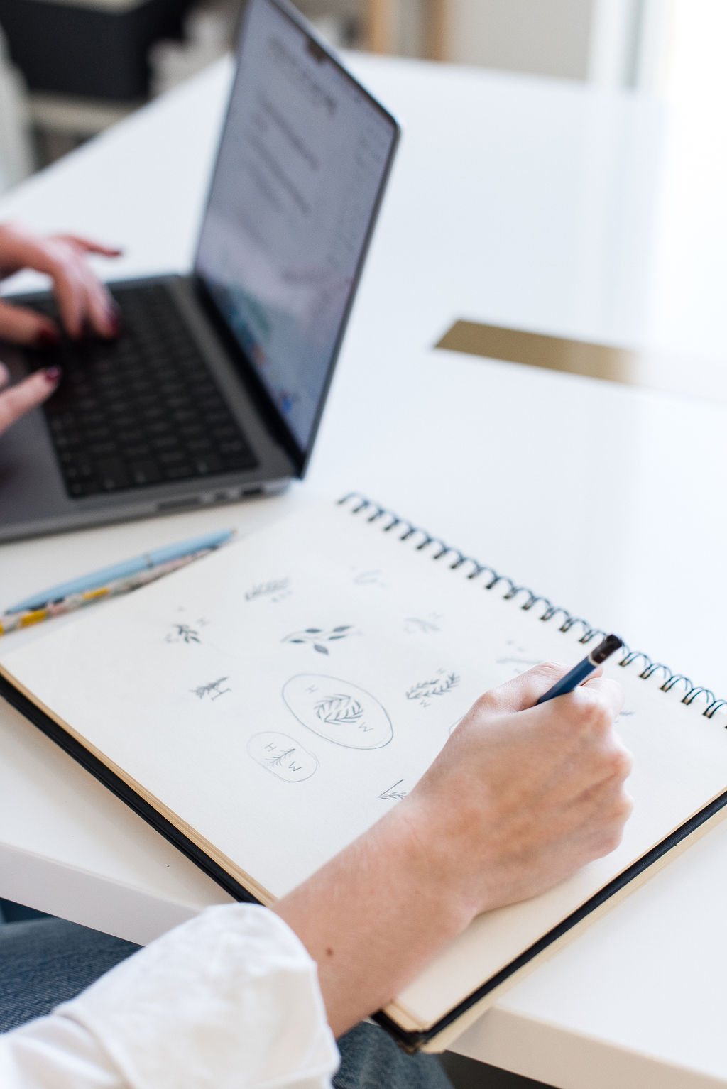 An employee sketching logo ideas in a notebook