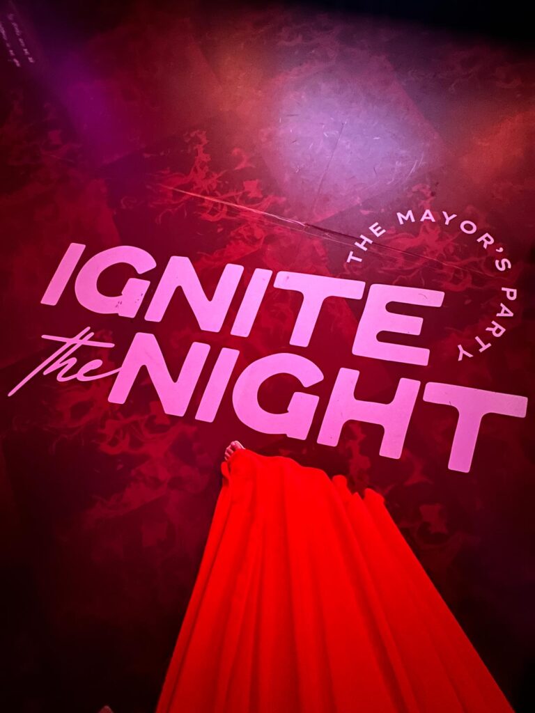 Carly standing above the Ignite the Night branded logo at the Mayors Party