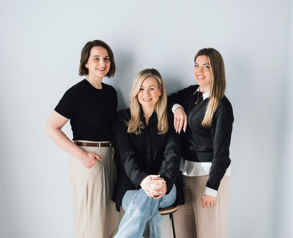 Three business strategists pose in a line